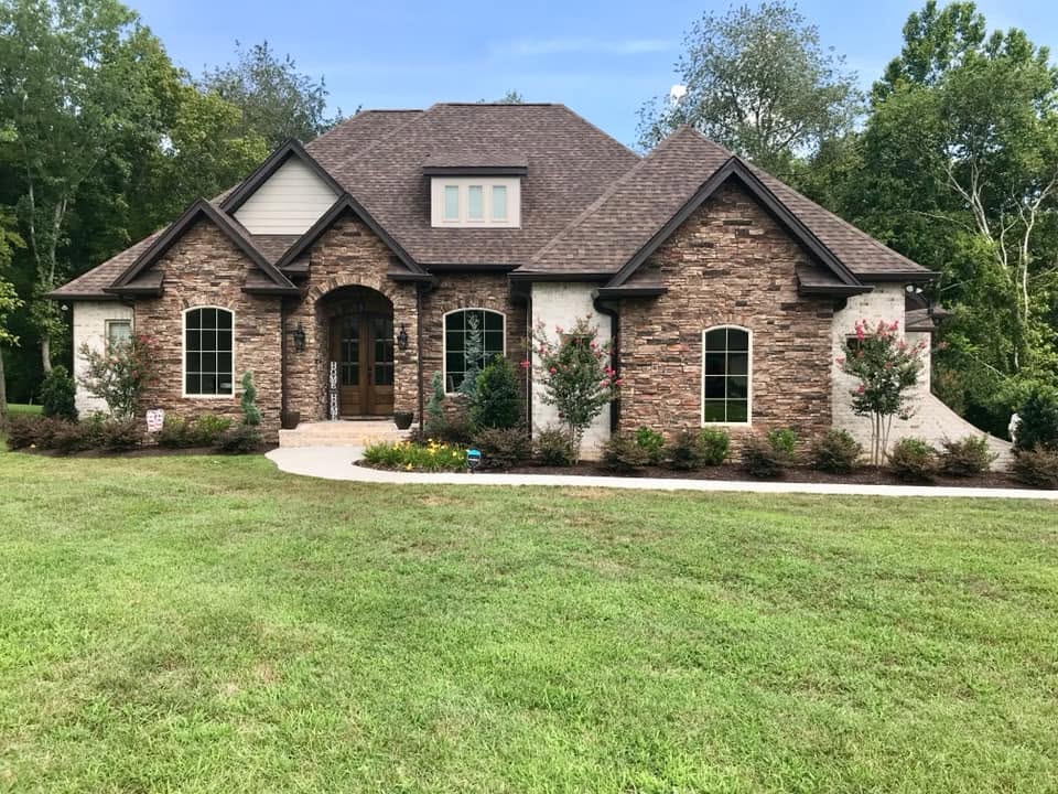 Stone and brick home with a new roof installed by Jonesall Inc.
