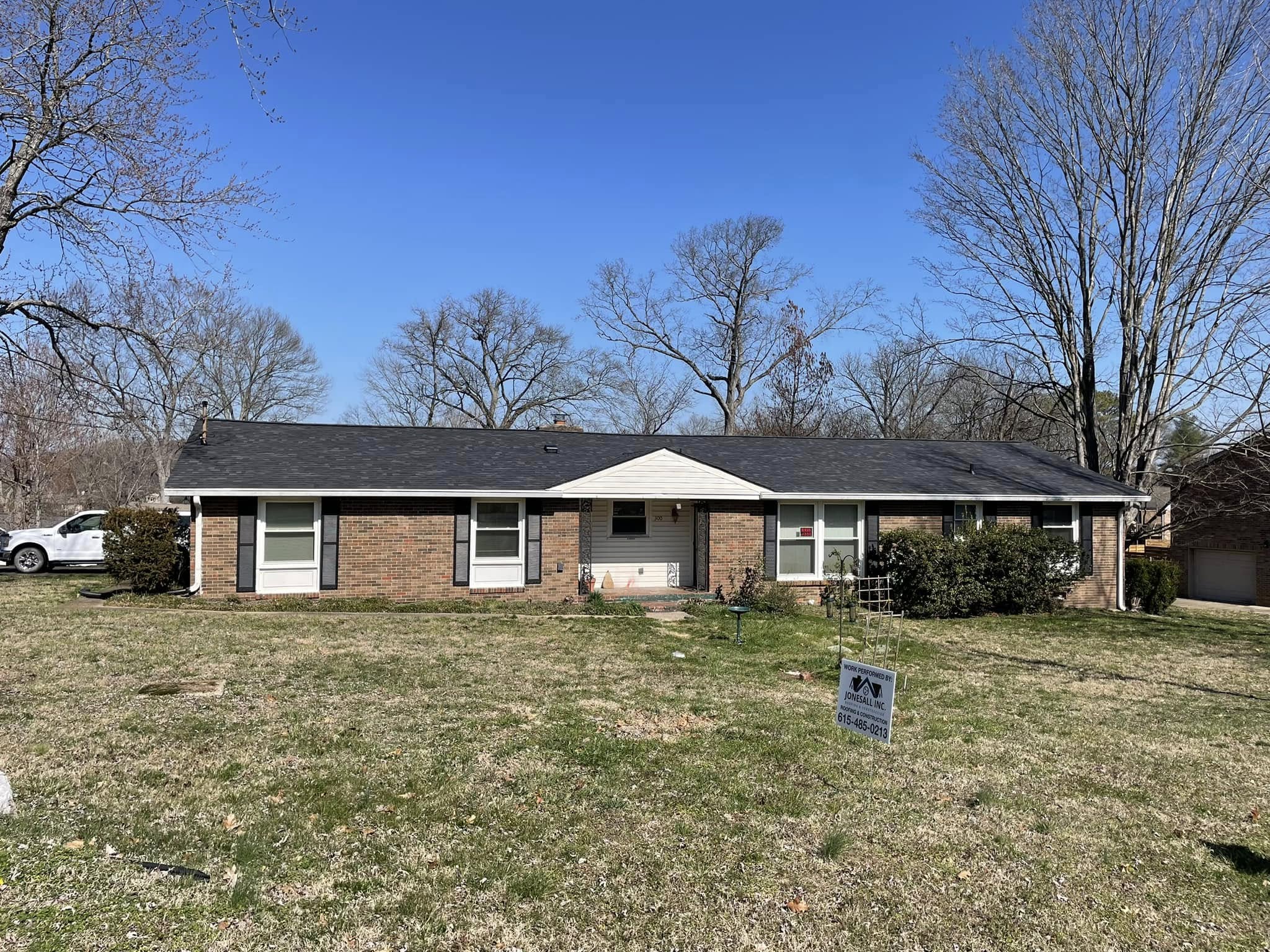 Brick ranch home with a new charcoal shingle roof and Jonesall yard sign